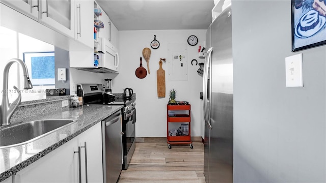 kitchen with white cabinetry, sink, dark stone countertops, light hardwood / wood-style floors, and appliances with stainless steel finishes