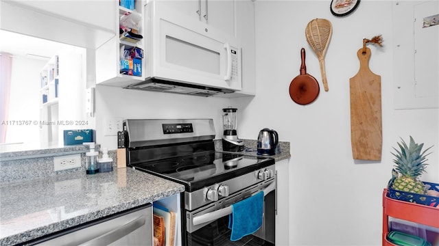 kitchen with white cabinetry, light stone counters, and appliances with stainless steel finishes