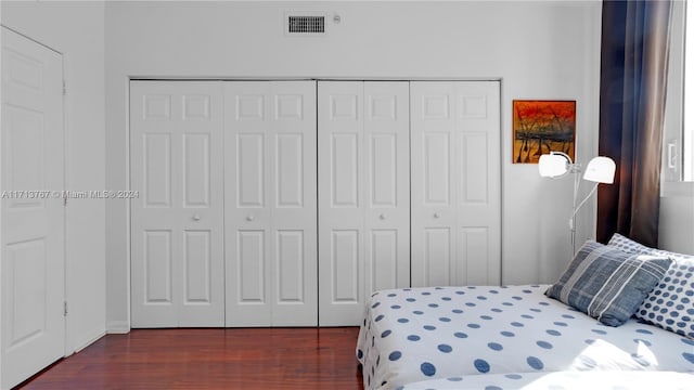 bedroom with dark hardwood / wood-style flooring and a closet