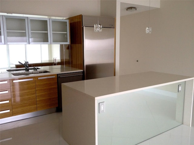 kitchen featuring appliances with stainless steel finishes, sink, light tile patterned floors, a kitchen island, and hanging light fixtures