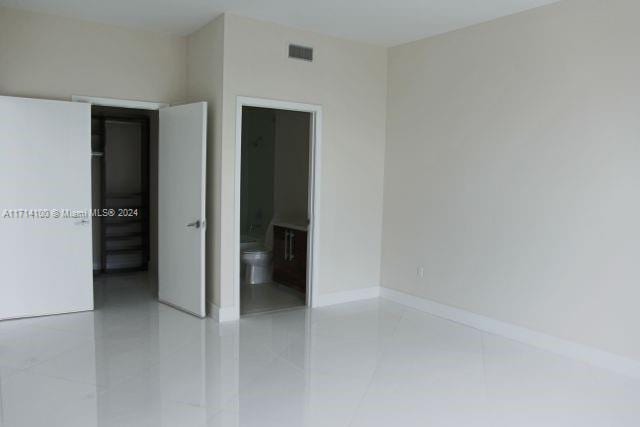 unfurnished bedroom featuring ensuite bathroom and light tile patterned floors