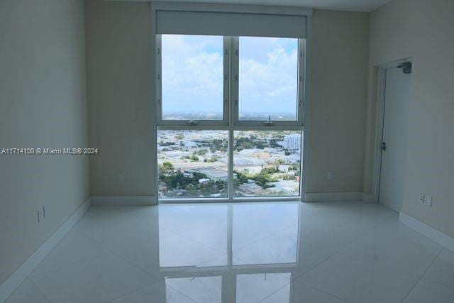 empty room featuring floor to ceiling windows and light tile patterned floors