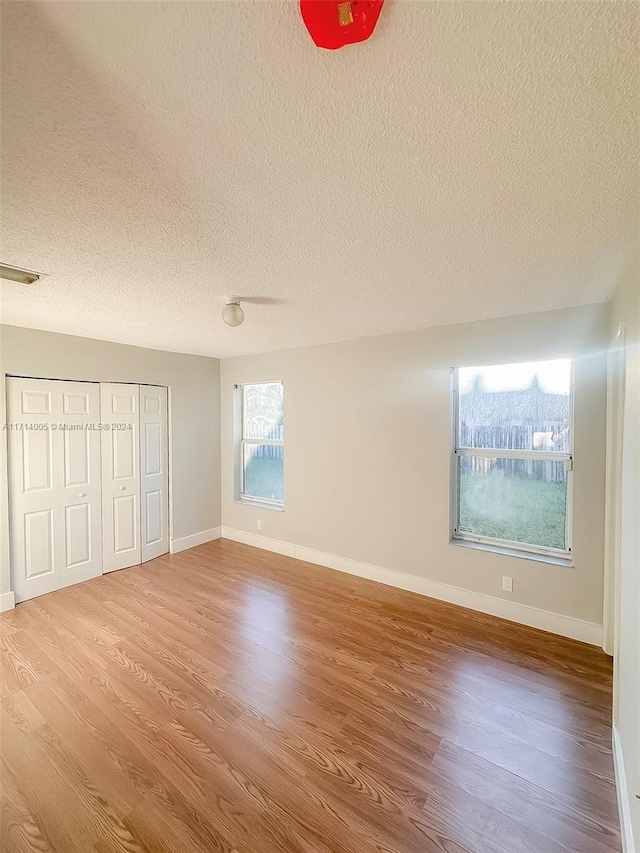 unfurnished bedroom featuring a closet, wood-type flooring, and a textured ceiling