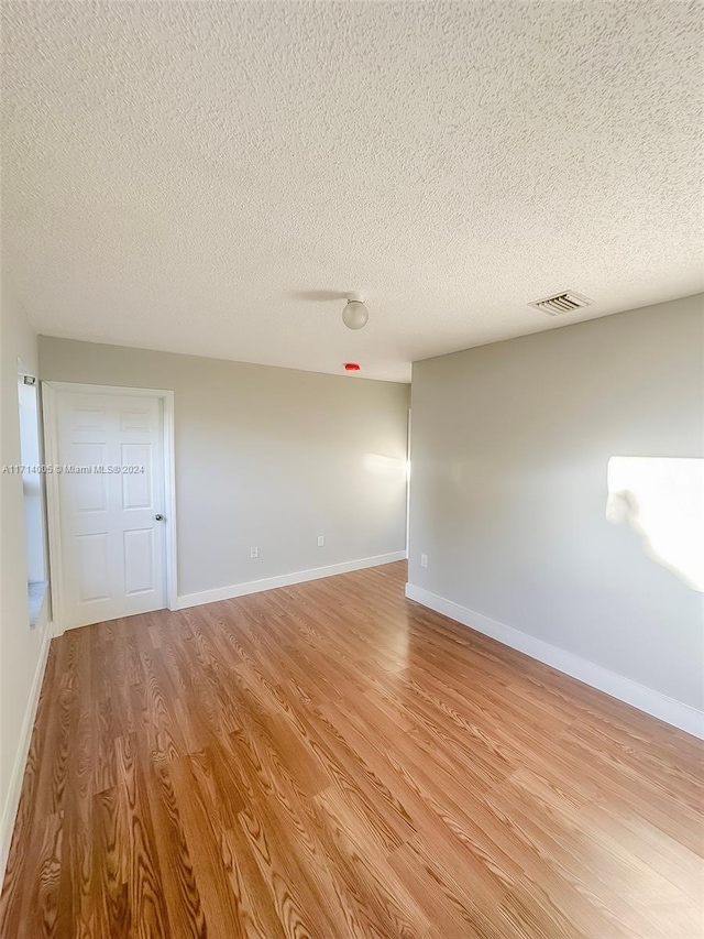 unfurnished room featuring a textured ceiling and light hardwood / wood-style floors