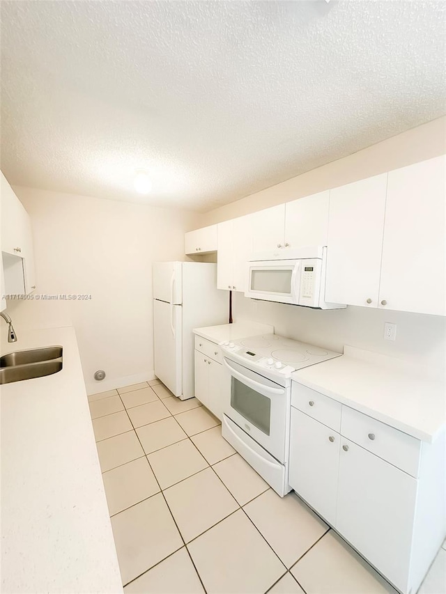 kitchen featuring sink, light tile patterned flooring, a textured ceiling, white appliances, and white cabinets