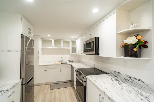 kitchen featuring sink, light stone countertops, light wood-type flooring, white cabinetry, and stainless steel appliances