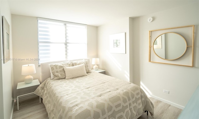 bedroom with light hardwood / wood-style floors and multiple windows