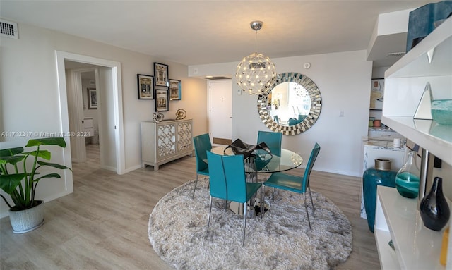 dining area with an inviting chandelier and light hardwood / wood-style flooring