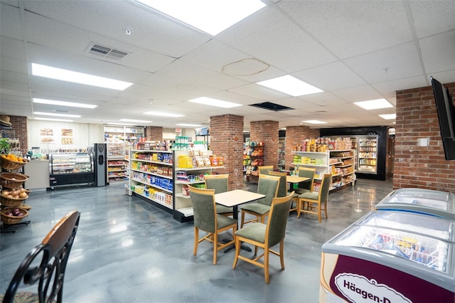 dining area with a drop ceiling and brick wall