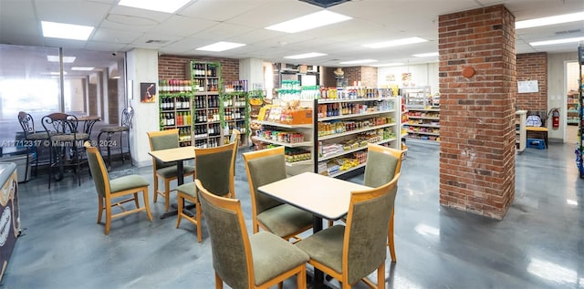 dining area with a drop ceiling and concrete flooring