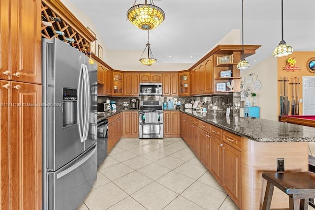 kitchen with backsplash, dark stone counters, hanging light fixtures, kitchen peninsula, and stainless steel appliances