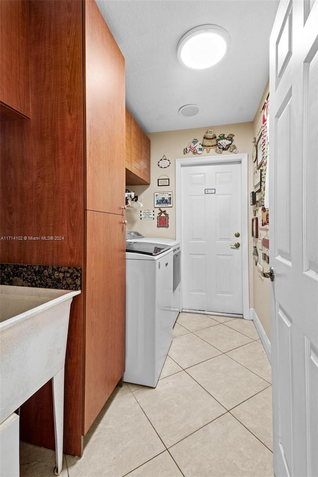 washroom featuring cabinets, sink, light tile patterned flooring, and washing machine and clothes dryer