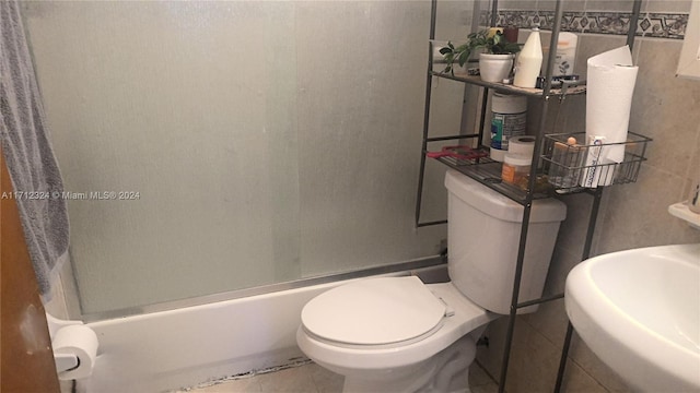 full bathroom with tile patterned floors, shower / bath combination with glass door, sink, and tile walls