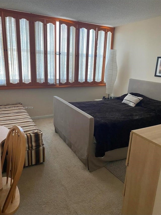 bedroom with a textured ceiling and light colored carpet