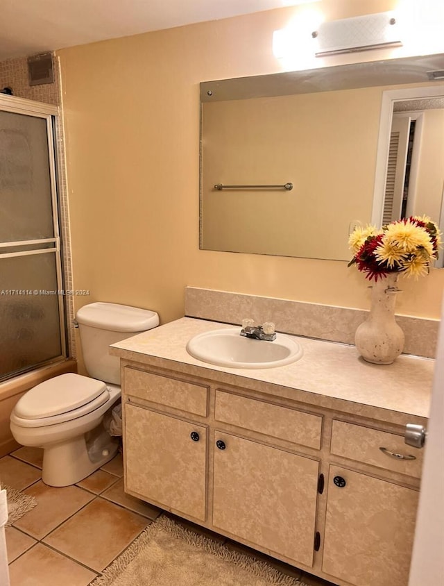 full bathroom featuring tile patterned floors, vanity, toilet, and enclosed tub / shower combo