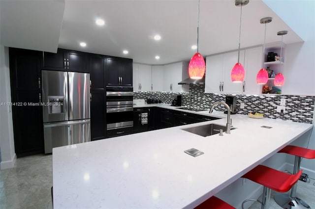 kitchen with sink, kitchen peninsula, pendant lighting, a breakfast bar, and appliances with stainless steel finishes