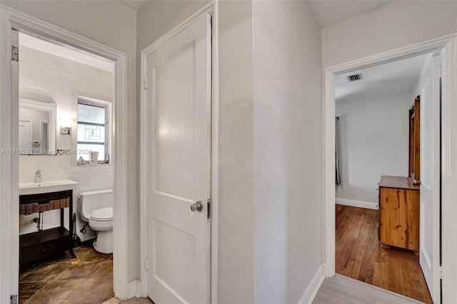 bathroom with hardwood / wood-style floors, toilet, tile walls, and sink