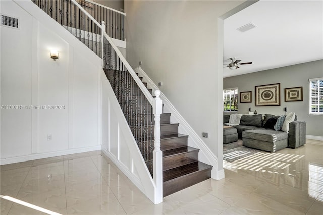 stairway featuring ceiling fan