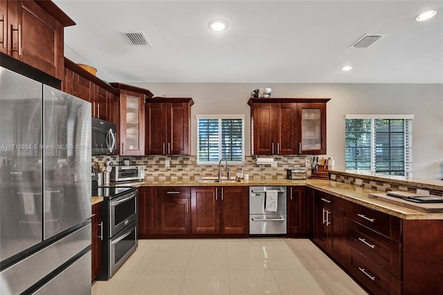 kitchen featuring sink, tasteful backsplash, light stone counters, kitchen peninsula, and stainless steel appliances