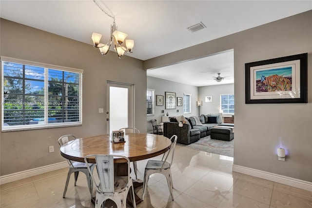 tiled dining area with ceiling fan with notable chandelier and a wealth of natural light