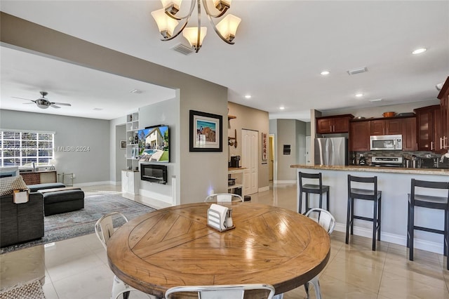 dining area with light tile patterned floors and ceiling fan with notable chandelier