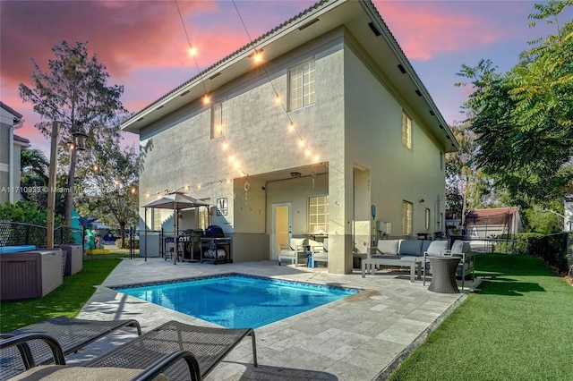 back house at dusk with a yard, a fenced in pool, and a patio area