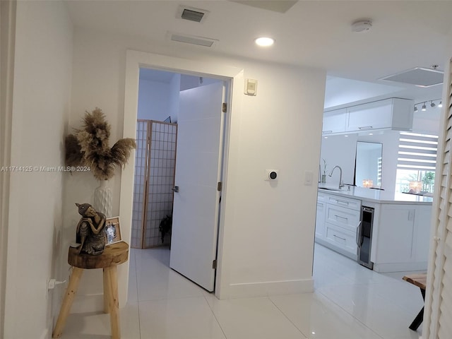 hall featuring light tile patterned floors, sink, and wine cooler