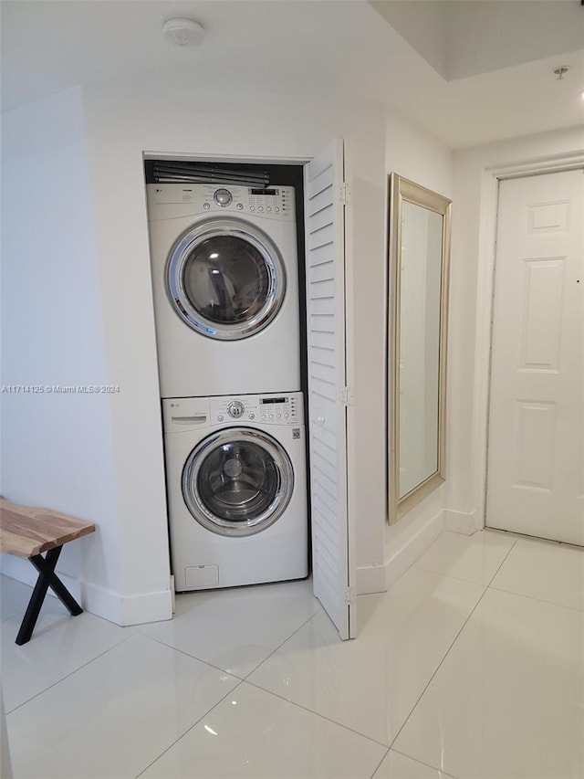 clothes washing area featuring stacked washer / drying machine and light tile patterned flooring