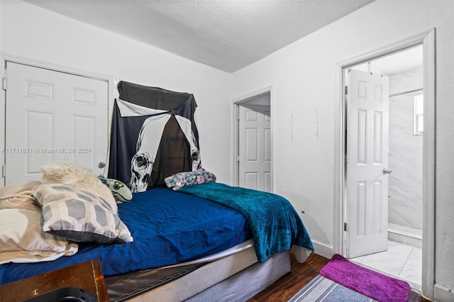 bedroom featuring hardwood / wood-style flooring, a textured ceiling, and ensuite bath