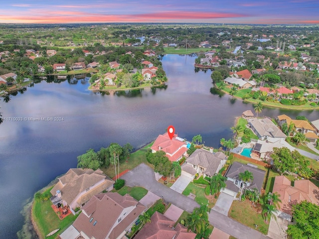 aerial view at dusk featuring a water view