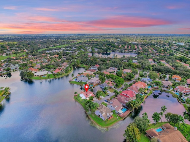 aerial view at dusk featuring a water view