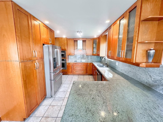 kitchen featuring light stone countertops, sink, stainless steel appliances, wall chimney range hood, and decorative backsplash