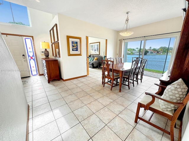 dining room with a water view, light tile patterned floors, and a textured ceiling