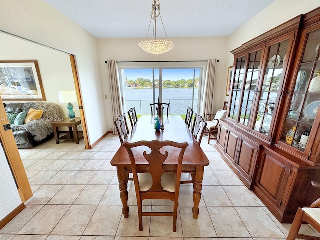 dining room with a water view, light tile patterned floors, and a textured ceiling