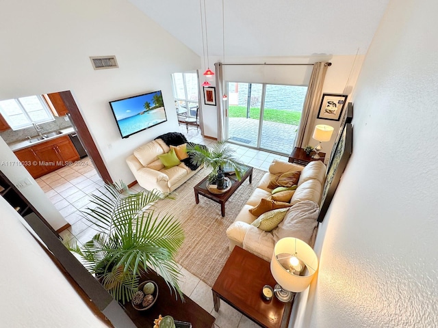 living room featuring high vaulted ceiling, light tile patterned floors, sink, and a wealth of natural light