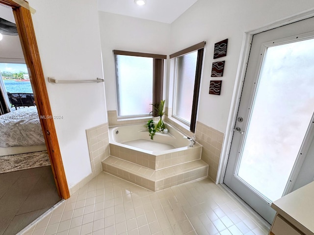 bathroom with a wealth of natural light, tile patterned flooring, and a relaxing tiled tub