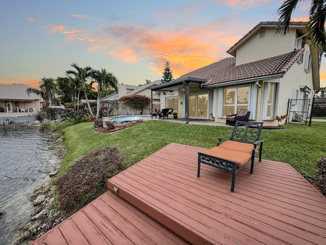 deck at dusk with a yard and a swimming pool