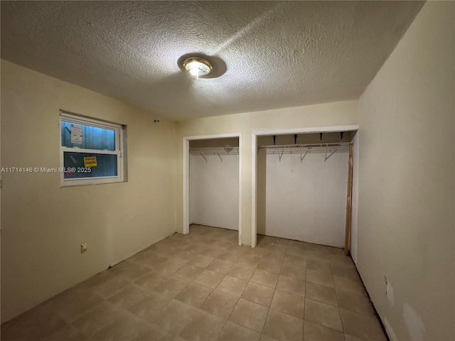 unfurnished bedroom featuring a textured ceiling and two closets