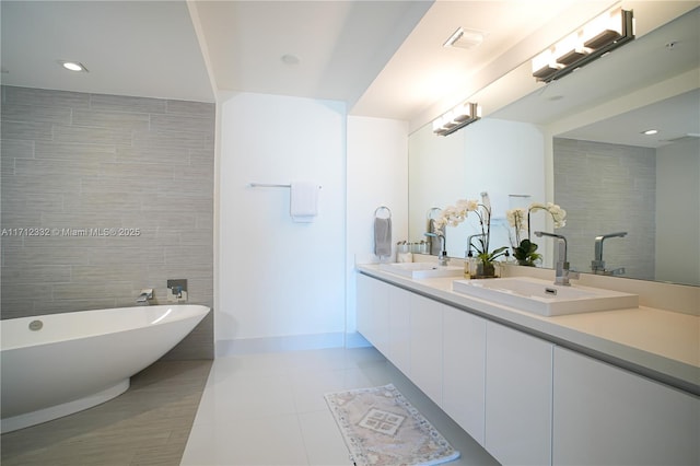 bathroom with a tub to relax in, tile patterned flooring, vanity, and tile walls