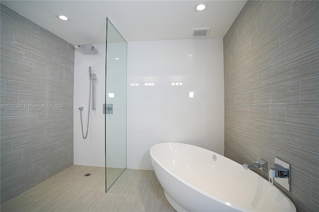 bathroom with tile patterned flooring, tile walls, and shower with separate bathtub