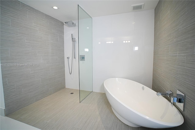 bathroom featuring tile patterned flooring, separate shower and tub, and tile walls