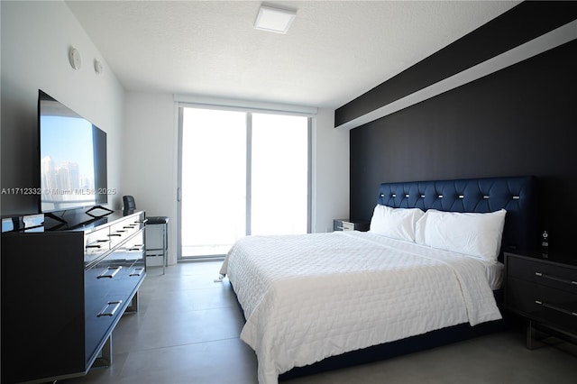 bedroom featuring a textured ceiling, concrete floors, and floor to ceiling windows