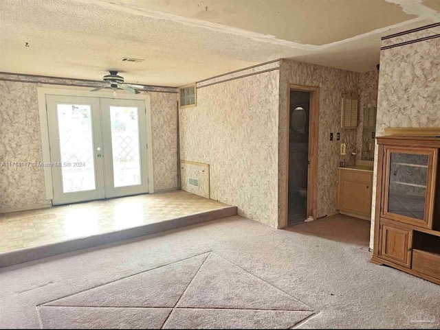 carpeted empty room featuring ceiling fan, french doors, and a textured ceiling