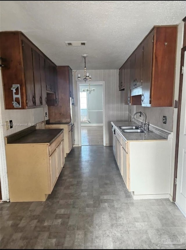 kitchen with a textured ceiling, a notable chandelier, and sink