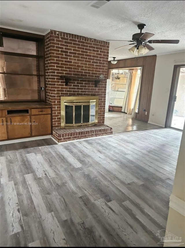 unfurnished living room featuring hardwood / wood-style floors, a textured ceiling, a brick fireplace, and ceiling fan