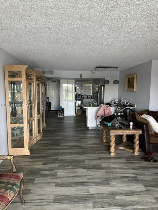living room with a textured ceiling, wood finished floors, and visible vents