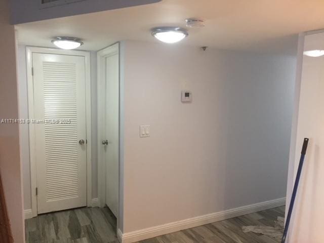 hallway featuring wood finished floors and baseboards