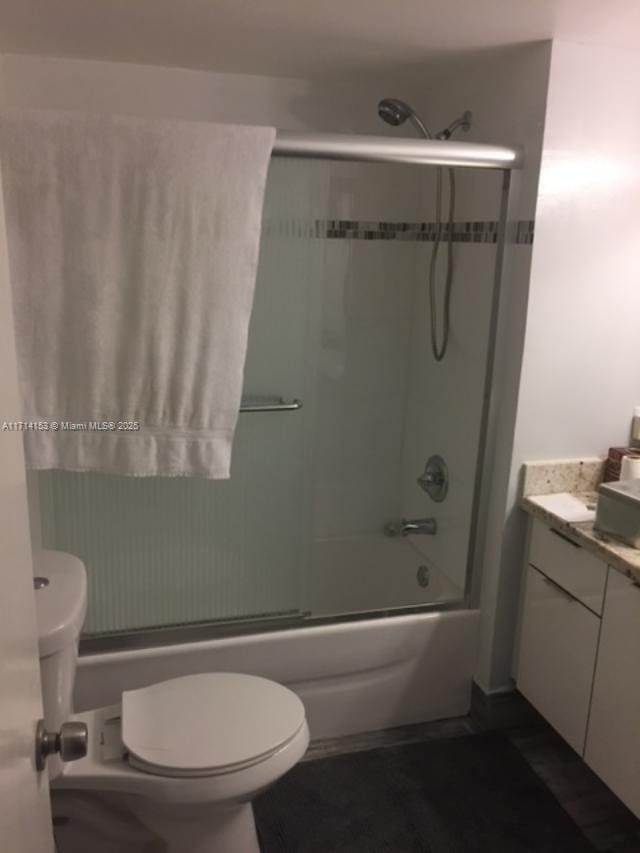 full bathroom featuring combined bath / shower with glass door, vanity, and toilet