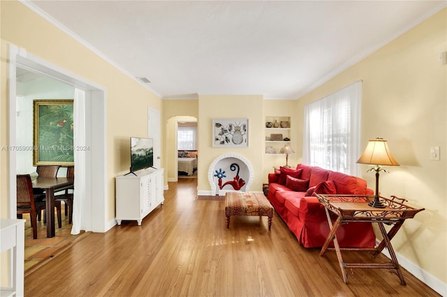 living room featuring plenty of natural light, hardwood / wood-style floors, built in features, and ornamental molding