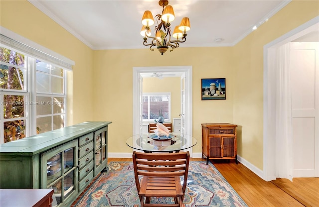 dining room with ceiling fan with notable chandelier, light wood-type flooring, and crown molding